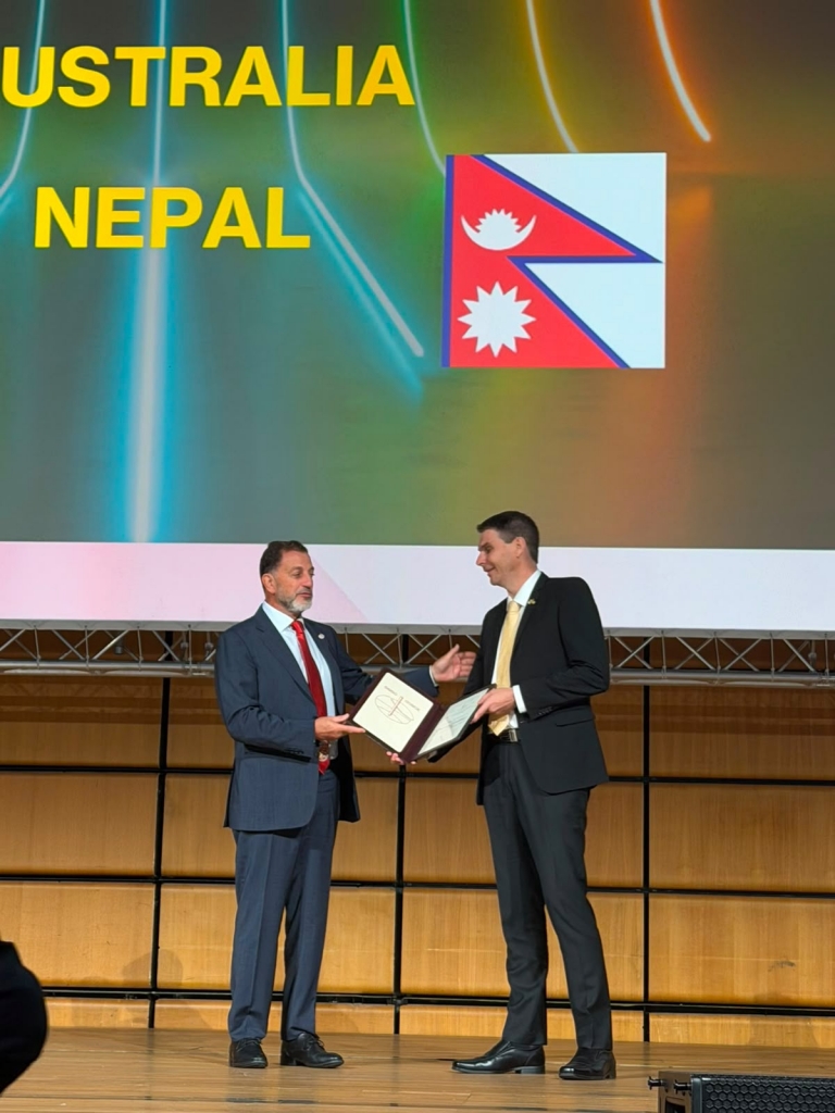 Two men in suits on a stage Description automatically generated